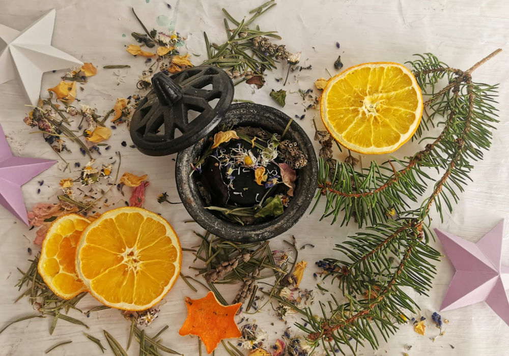 Mystische Räucherpraxis in den Rauhnächten - Kräuter, Harze und Weihrauch verschmelzen in einem spirituellen Ritual. Eine handverlesene Auswahl von Räucherutensilien liegt vor einem festlichen Hintergrund aus Kerzenlicht und natürlichen Elementen.